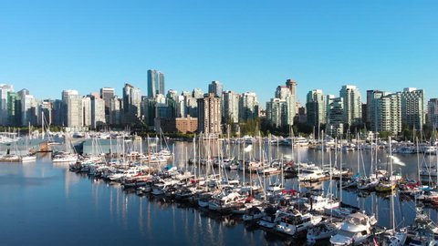 Aerial view of Vancouver Harbour, flying over boats with downtown buildings in the background during daytime in Vancouver, British Columbia, Canada. 