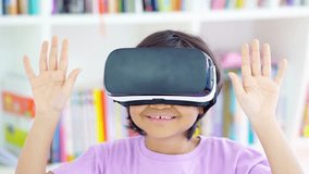Cute little girl using virtual reality goggles while standing in the library and gesturing with her hands.