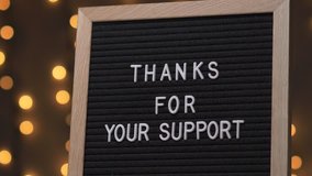 Black letter board with THANKS FOR YOUR SUPPORT Written on it with white letters. Camera rotating around the sign showing the beautiful bokeh balls in the background. - Powered by Shutterstock - Get 15% off with code: PIKWIZARD15