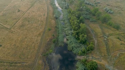 Aerial view over the river stream. Flying over the marshy area. 4k video