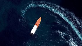 Video from above, aerial view of a racing boat floating on a transparent and turquoise sea. Sardinia, Italy.