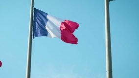 French flag fabric waving in front of blue sky. Tricolor flag of France