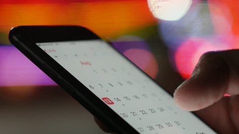 User looking at calendar dates on a smartphone - schedule for summer holiday vacation, business meatings, appointments, new initiatives concept