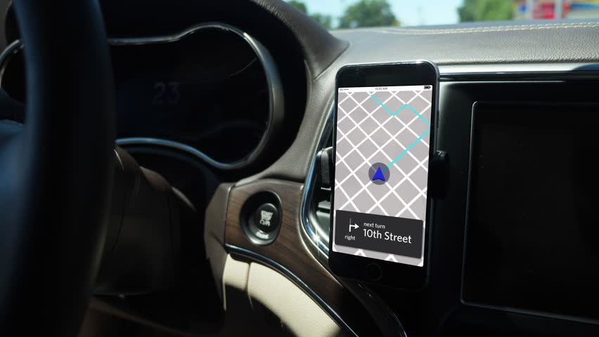 A smartphone attached to the dash on a vent holder in a moving car shows a ride sharing app with route in progress. App screen simulated.	 	