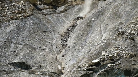 Slow motion rockfall in the mountains close up. Lumps of stones fall down from the melting glacier