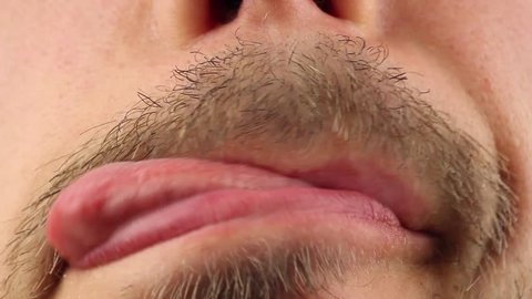 man with mustache licks his lips by tongue, two times, closeup macro 