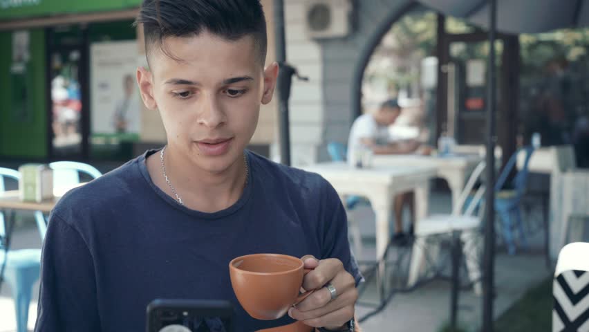 Portrait of a cheery and sportive man with a crew haircul drinking coffee and smiling cheerfully in a modern cafeteria on a sunny day 