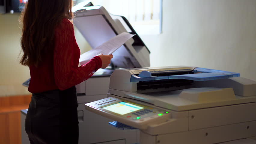 Secretary woman working in office with documents. Brunette female making documentation copies using scan machine. Shot in 4K (UHD). | Shutterstock HD Video #1015191202