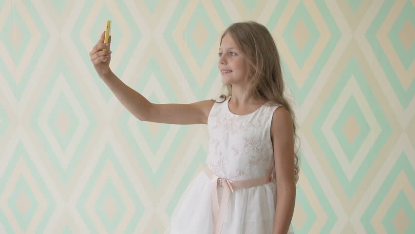 Happy little girl take a selfie with her smartphone at home