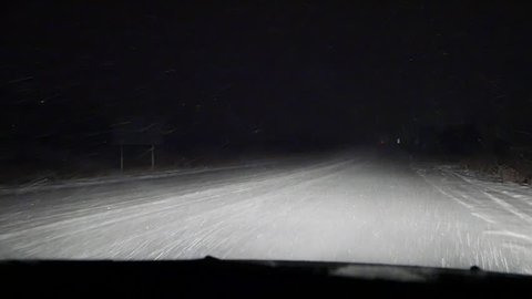 Night drive in a car in snowfall, snowstorm nights. Bad non-flying weather. Low beam of headlighs. Road safety