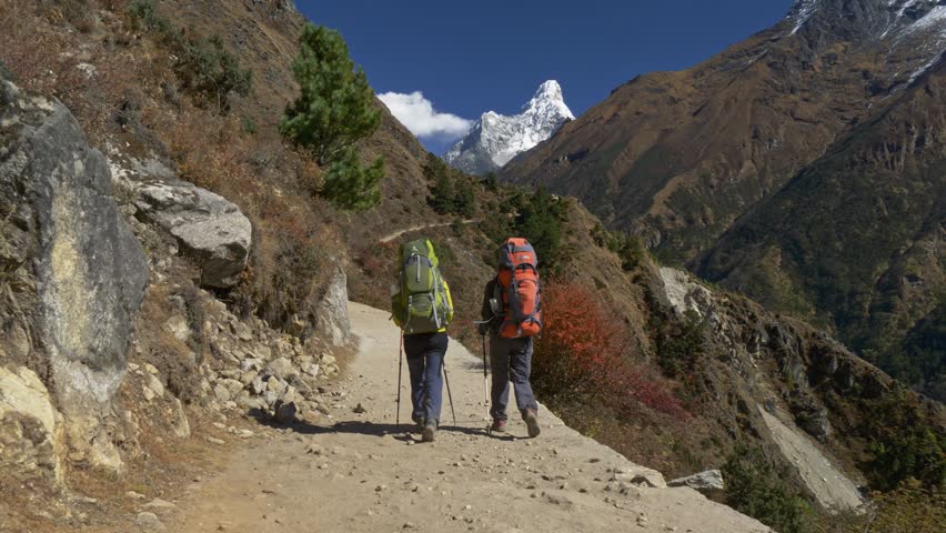 Trekking in Nepal. Two hikers with backpacks are on path. Everest Base Camp trek. Sagarmatha national park, Nepal. Steadicam shot.