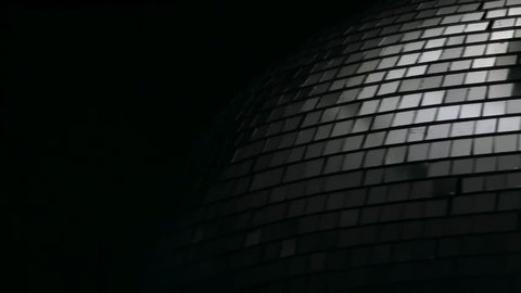Mirror disco ball rotates close up . Black background