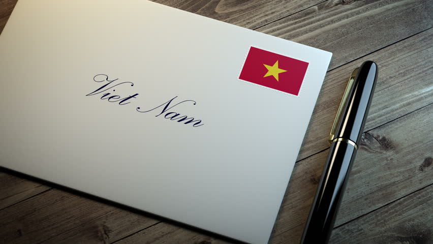 Country name written on a card or envelope in cursive font with a sleek pen on a wooden table surface under beautiful classy light. Stamp in the corner shows the flag of Viet Nam
