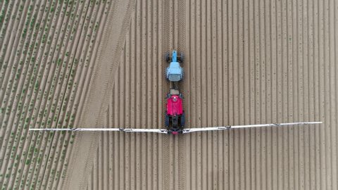 Aerial top down view tractor spraying herbicides also commonly known as weedkillers are chemical substances used to control unwanted plants and used before crop is grown on field 4k high resolution
