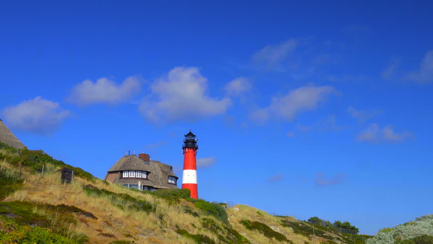 Beautiful red white Lighthouse with dunes and thatched house on Sylt vacation Island - time lapse clip Royalty-Free Stock Footage #1015214086