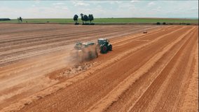 Aerial view of tractor with combine harvester that makes stakes of hay. Harvest of wheat field Agriculture and environment in European Union. 4K Drone video.