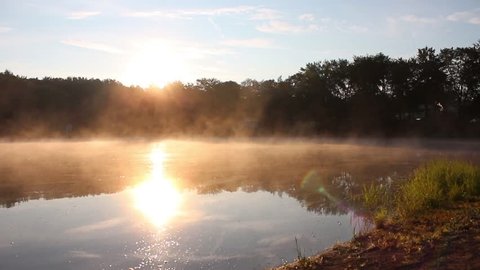 Fog drifting on a lake in the morning light.