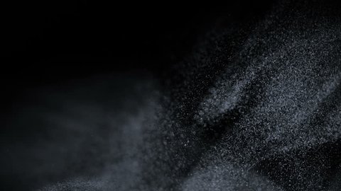 Motion performed by small particles. Floating particles on black background. Slow motion.