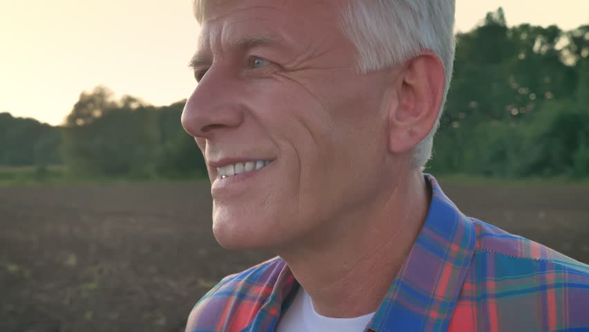Portrait of old farmer looking at camera and smiling, cultivated field during morning in background, happy and joyful | Shutterstock HD Video #1015231315