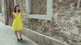 Young attractive woman in yellow dress walking by the brick wall and contemplating her problems.