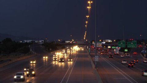 View of traffic on freeway with storm above and lightning strikes viewed from over interstate overpass.