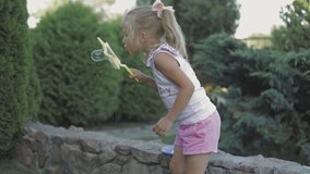 little girl blowing soap bubbles in summer park. fullhd slow motion video shooting by handheld gimbal