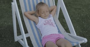 Girl sits in chair and relaxes in garden. 4k video shooting by handheld gimbal