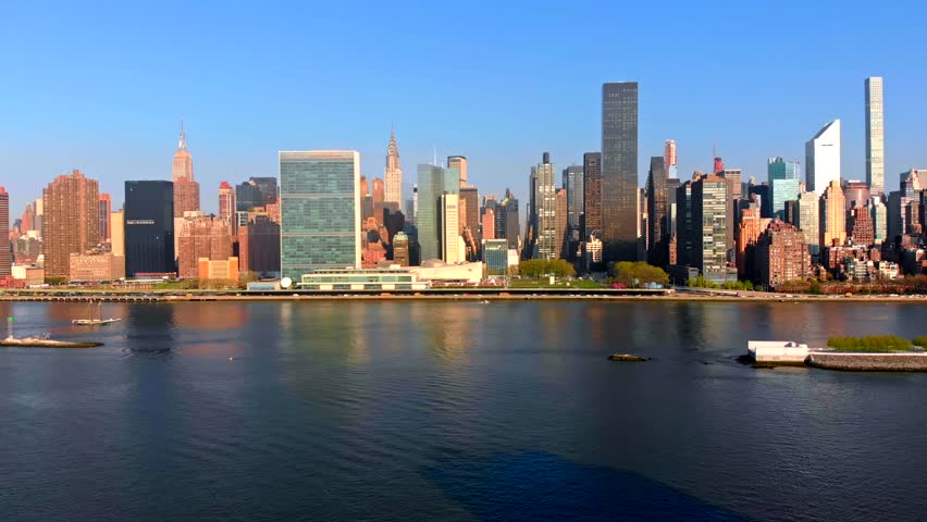 Aerial Drone Footage panning left of New York City Manhattan skyline over East River viewed from Gantry Plaza State Park in Long Island City