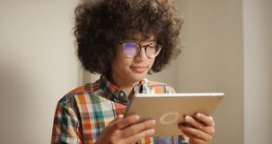 4K Close up young man with glasses & big hair streaming media on digital tablet