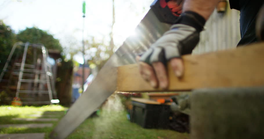 4K Closeup piece of timber being cut by man with a saw in the garden. Slow motion. | Shutterstock HD Video #1015270087