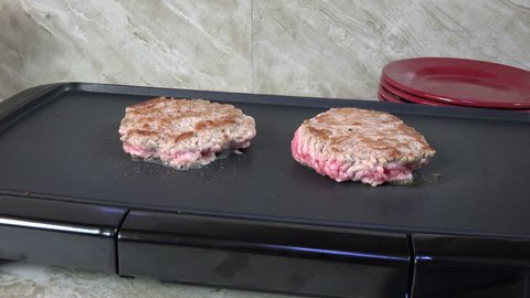 Sausage patties simmering on an electric grill