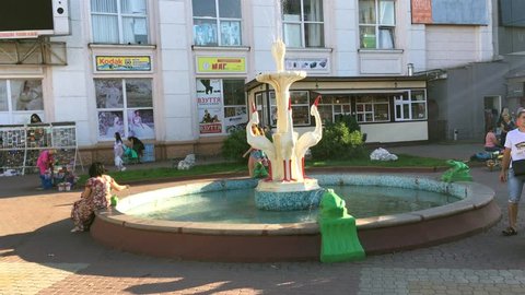 Khmelnitsky, Ukraine, August 2018: - People walk near the fountain in the form of a crane in the city center. A summer sunny day.