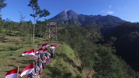 YOGYAKARTA INDONESIA, AUGUST 21 2018 : Student raising national flag of Indonesia in slow motion under clear sky and mountain. INDONESIA INDEPENDENCE DAY