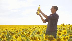 Man farmer hand hold lifestyle bottle of sunflower oil the field at sunset. Sunflower oil improves skin health and promote cell regeneration. slow motion video. man farmer agriculture plastic bottle