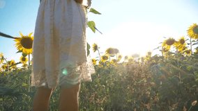 Happy little girl runs happy free across the field with sunflowers. slow motion video. smelling big sunflower on summer field. Delight of a pleasant smell. Summer holiday. lifestyle concept happiness