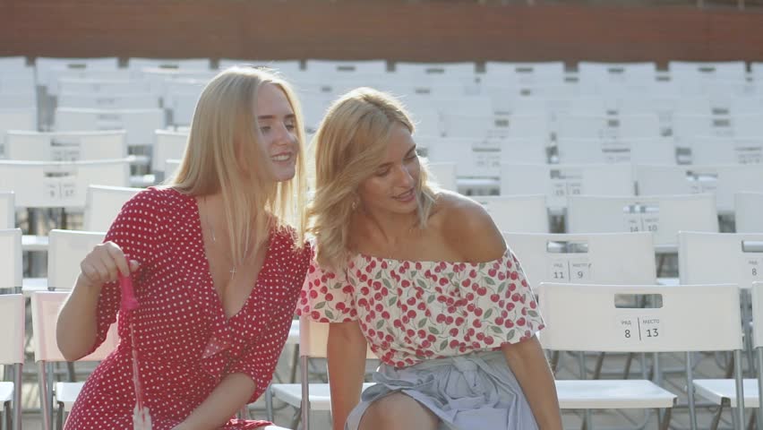 Two attractive beautiful young blond women blow bubbles in the park and are happy on sunset. Girlfriends in park. Slow motion 