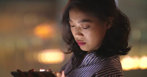 Close up of one young asian woman using tablet in cafe at night with city background, 4k