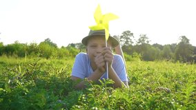 Closeup portrait of happy child laying on green grass in countryside meadow playing with yellow toy. Happy summer holidays concept. Real time full hd video footage.