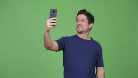 Happy Hispanic man video calling with phone