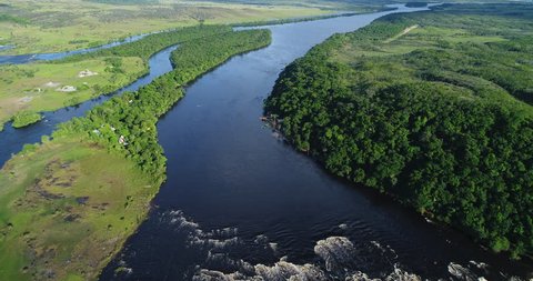 Aerial shot over the Amazon River landscape, beautiful forests and small towns, canoes and fishing boats are seen on the river beach. National park Canaima, Venezuela