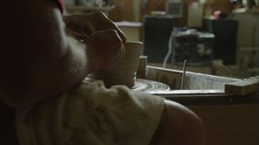 Close up of man shaping clay into bowl on pottery wheel with tool / Spring City, Utah, United States