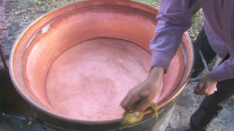 Making domestic brandy. Man prepares and washes cauldron 