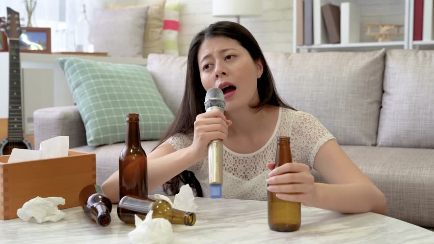 Asian heartbroken woman singing karaoke in her living room. She shouted and yelled to release the pain in her heart. | Shutterstock HD Video #1015316416