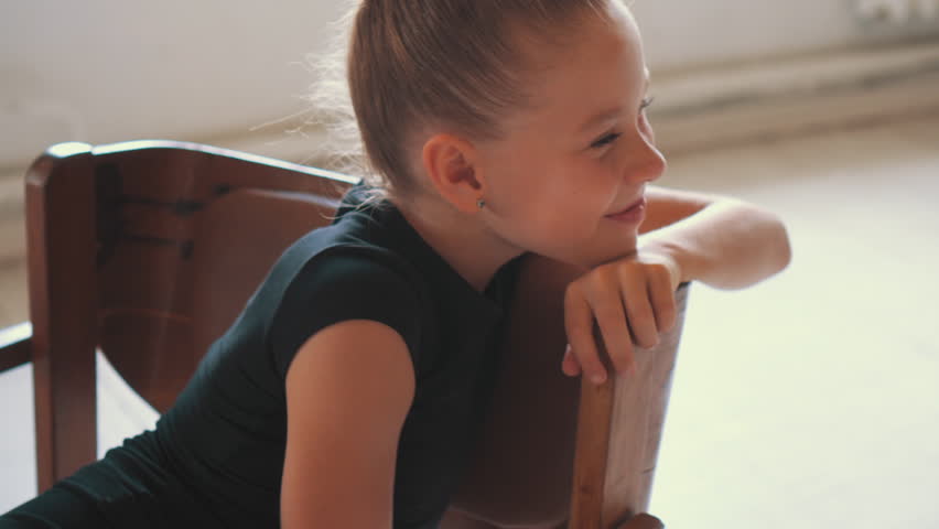 Dreaming young gymnast sitting on chair at dance studio