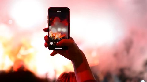 Taking a photo with mobile phone iPhone during rock band music performance concert on stage