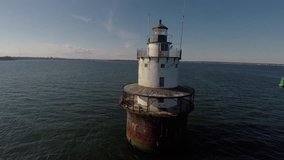 Orbiting drone shot from close up of a light house in the middle of the ocean slowly getting further.