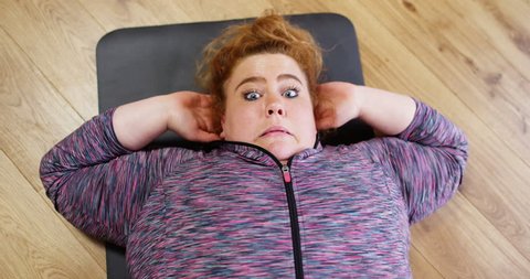 4K High angle view unfit obese woman with determination trying to do a sit up. Slow motion.