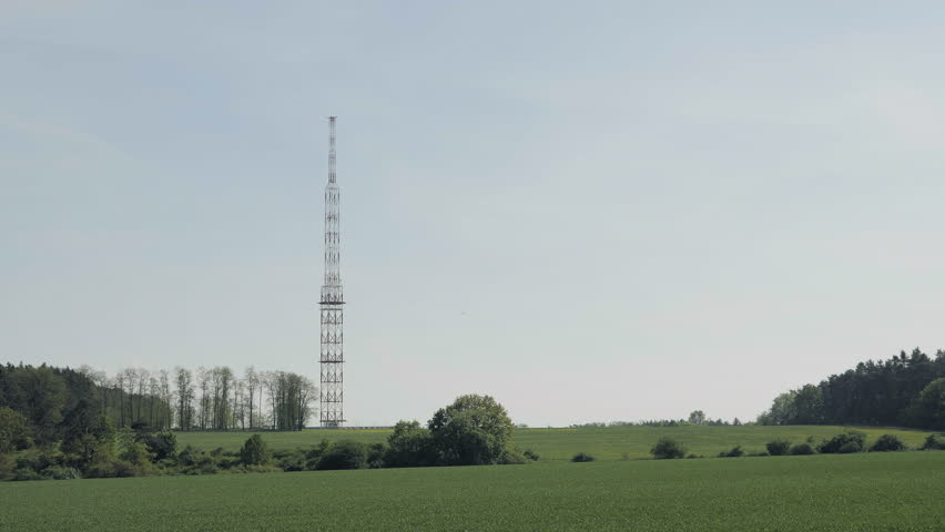 Red-white communications tower, sky in background. Satellite tower, transmission antenna telephone and television signals