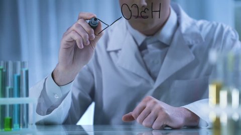 Scientist writing chemical formula on transparent board, pharmaceutical research