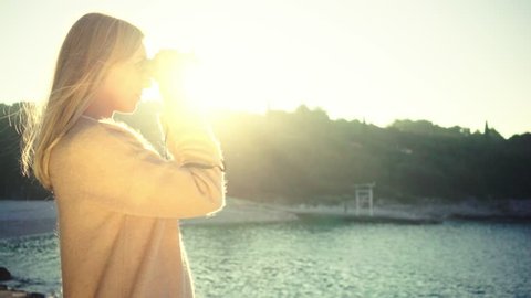 Happy woman through binoculars on summer day at sunset on a sea background Stockvideó